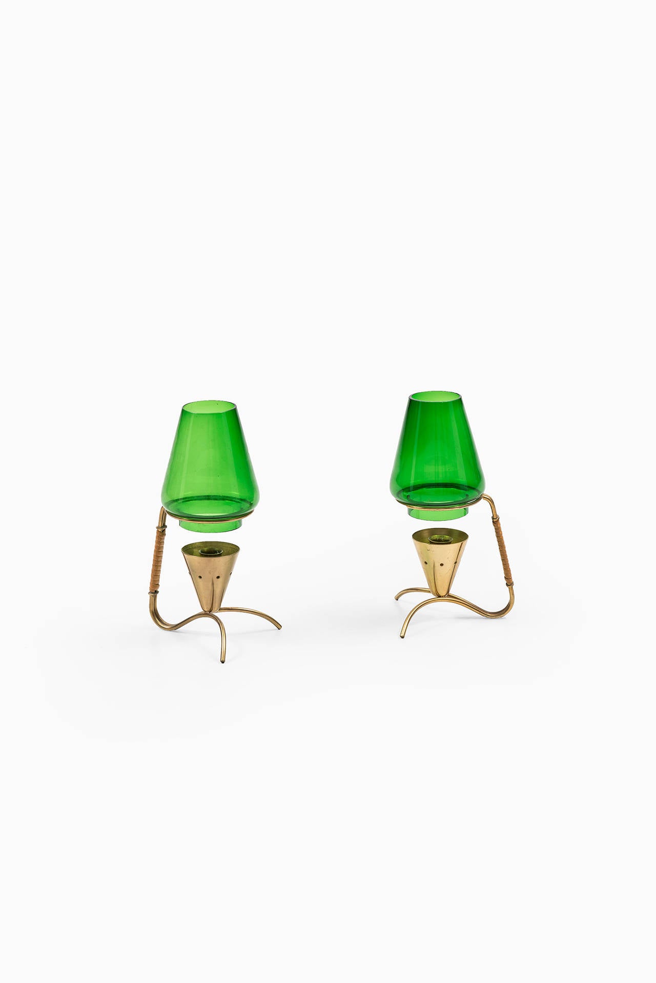 A rare pair of candlesticks in brass, with cane detail and green glass designed by Gunnar Ander. Produced by Ystad metall in Sweden.
