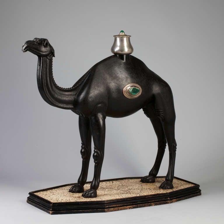 Anglo Indian carved ebonized Hartwood Camel with silver and malachite  ornament . Base is decorated with cracked  ostrich egg shell
Base and ornament probably added