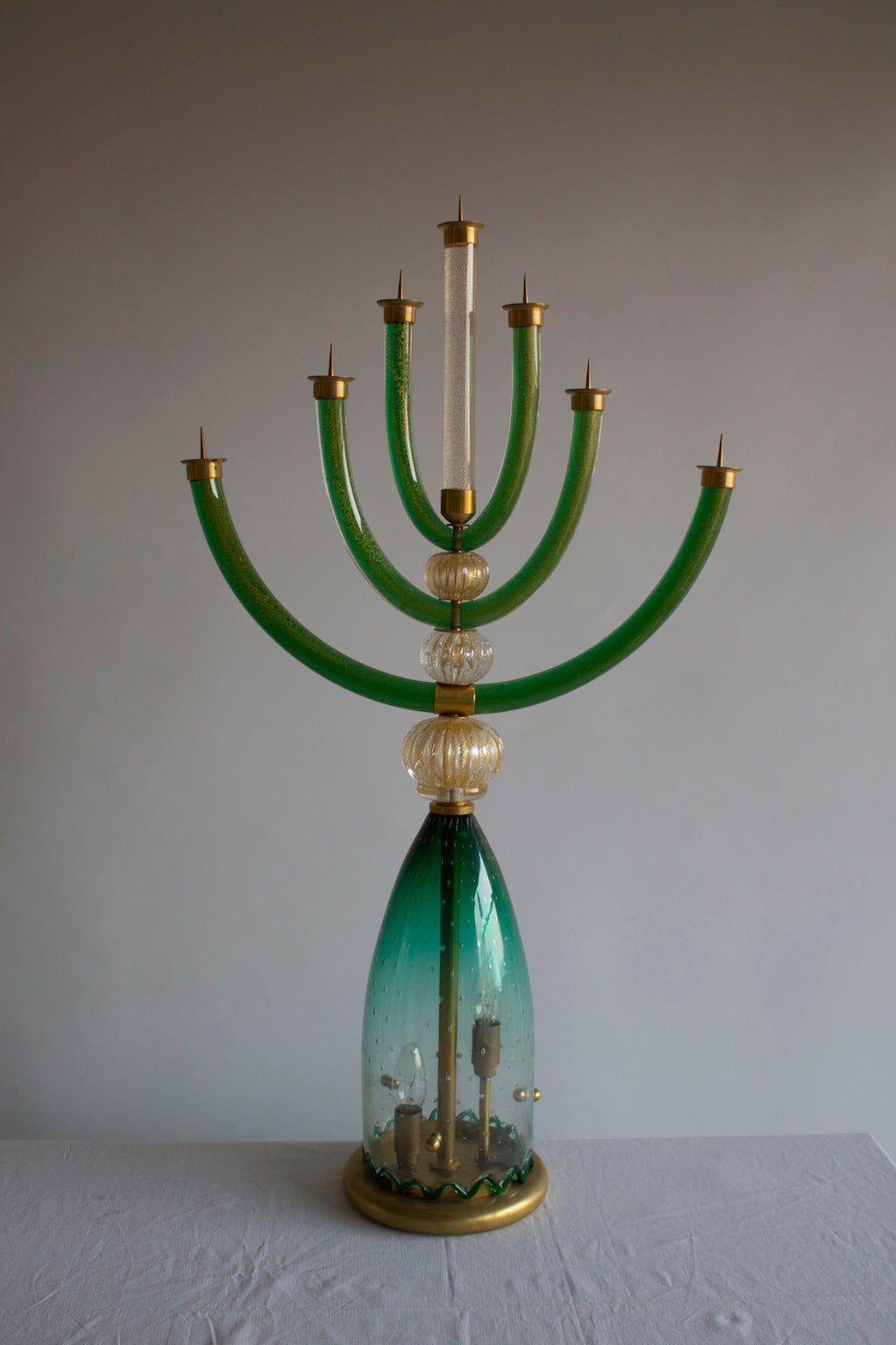 Amazing  and rare Murano Menorah in green and transparent color with gold finishings, in excellent original condition, from circa 1950s, with a brass frame, and  inside the base there is two lights. The Menorah is 37 inches high, 8 inches deep by 21