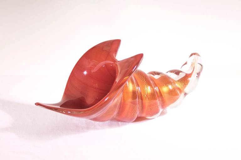 Exclusive Italian Italian Sculpture Red Shell in Blown Murano Glass by Romano Donà, 1980s.
The sculpture represents a red shell submersed in a thin and elegant transparent film of gold glass. The Sculpture is created by the art glass maker Romano