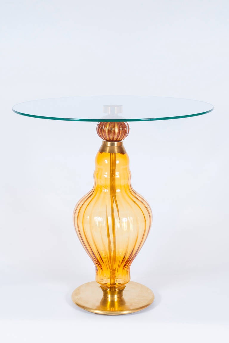 Elegant handcrafted Italian Venetian cocktail table, in blown Murano glass, amber color, dated 1990s.
The portrait is composed by an elegant brass frame with amber bowl and a red coral gold sphere; on top of that a circular plate.
This masterpiece