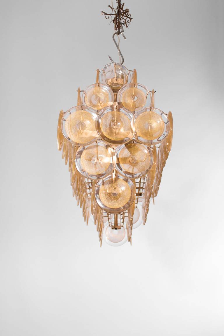 Amazing and spectacular Italian Murano chandelier, attributed to Mazzega, circa 1970s, composed by circular elements in transparent glass with in the middle a circular gold submerged, all is supported by a colored gold frame. The chandelier is 26