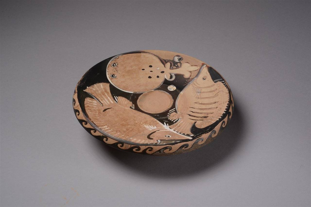 An ancient Apulian Greek red-figure fish plate, dating to the 4th century BC.

Sitting upon a short stem base, with two bream, two molluscs and a spotted torpedo fish around a central garum (fish sauce) recess. The shoulder of the plate decorated