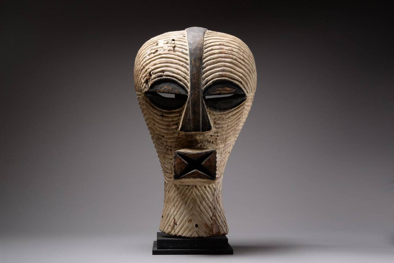 A striking African tribal Kifwebe mask, produced by the Songye peoples, early 20th century.

The wooden mask of powerful abstract form, the median crest on the head becoming a triangular nose, the two eyes of coffee-bean form, the rectangular