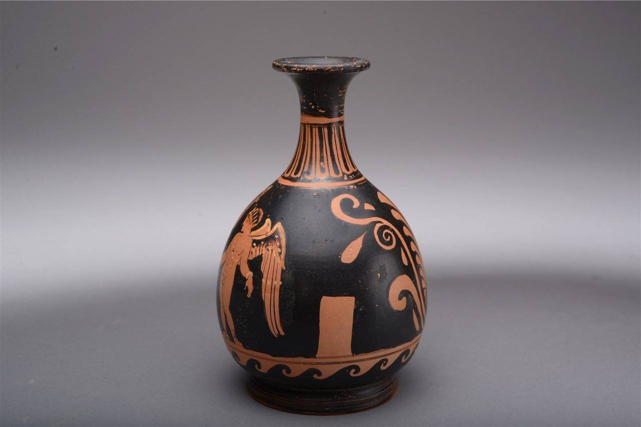 A particularly finely painted ancient Greek Apulian red-figure bottle, dating to the 4th century B.C.

A classically elegant form, sitting on a disc base, with a squat piriform body rising to a narrow neck and everted trumpet-like rim.

The