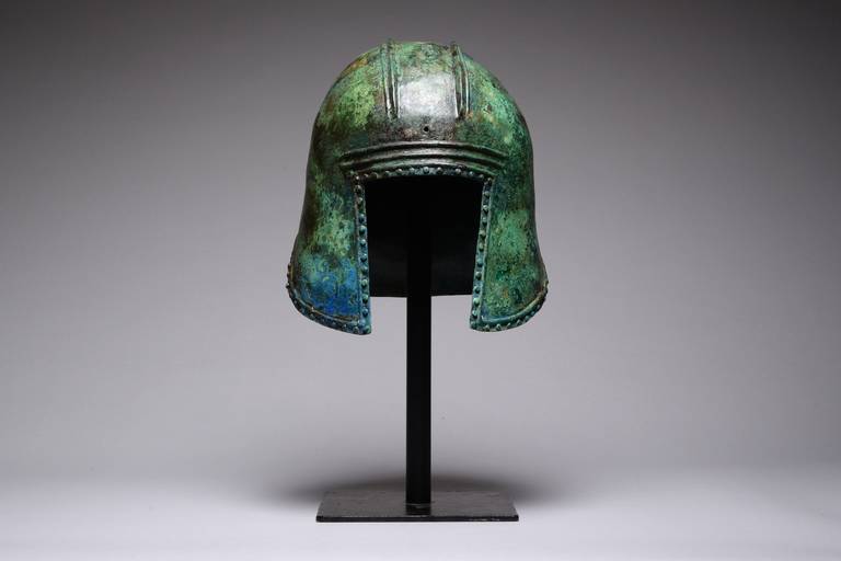 An ancient Greek Illyrian bronze hoplite helmet, dating to around 550-450 BC.

The helmet is of typical Illyrian form, with open face, pronounced cheek-flaps, high-dome and neck-flap. A perforation in the front centre and two above the neck flap