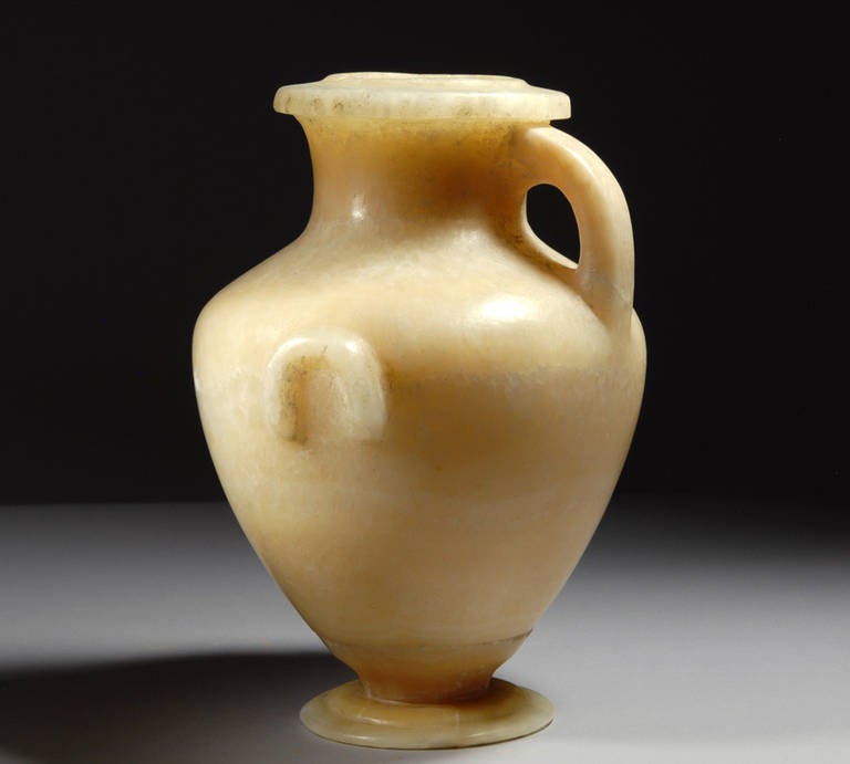 A beautiful, very rare and well provenanced Ancient Egyptian alabaster Hydria, dating to the 3rd Century BC.

The two part Hydria with circular base, acorn shaped body, short cylindrical neck, flat rim with arched handle at the back and two