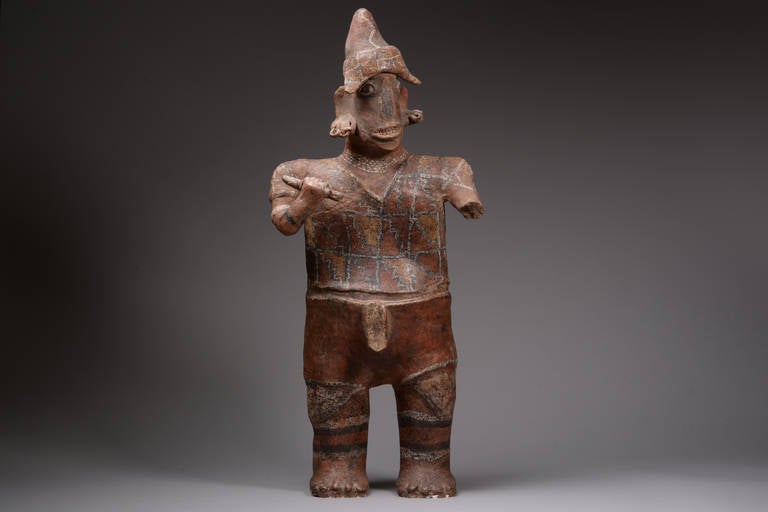 An ancient Pre-Columbian Nayarit figure of a warrior, dating to the Proto-Classic period, 100 BC-250 AD.

A long serpent-like face, grinning through the fleshy lips, with a set of prominent teeth and the eyes set impossibly wide on the head –