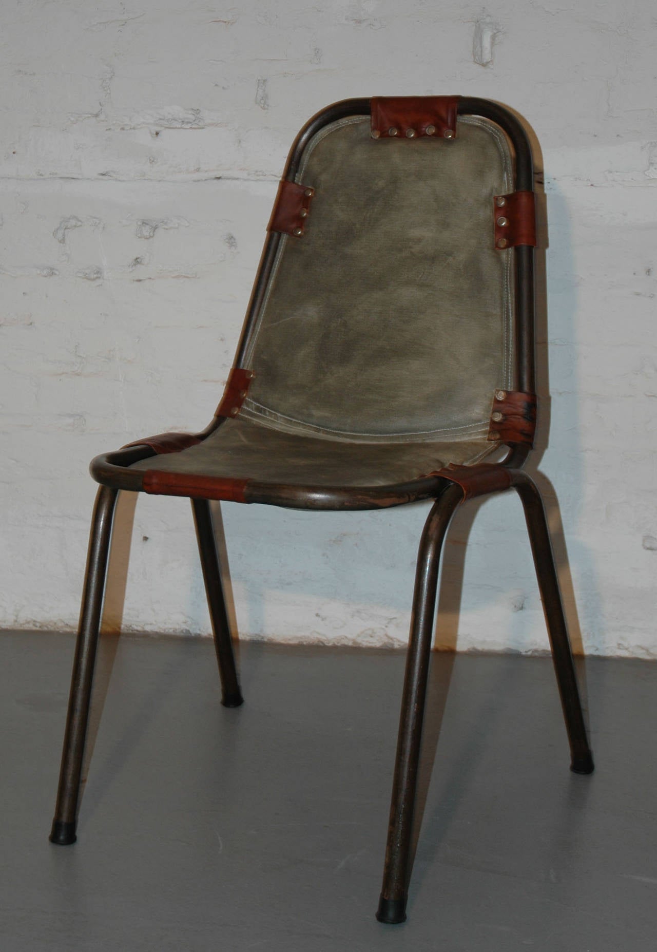 This chair was designed by Charlotte Perriand in the 1960s for the ski center Les Arcs in the French Alps. The shown sample is a different model with canvas (normally in leather) and with a larger steel tube.
