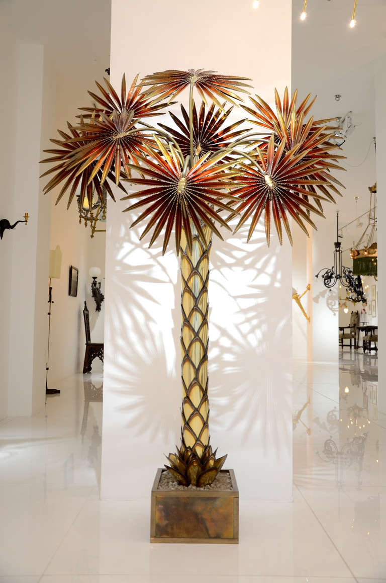 Gilded metal floor lamp representing a red palm tree composed of nine palm leaves which hide bulbs. We can electrify this floor lamp with U.S. standard.