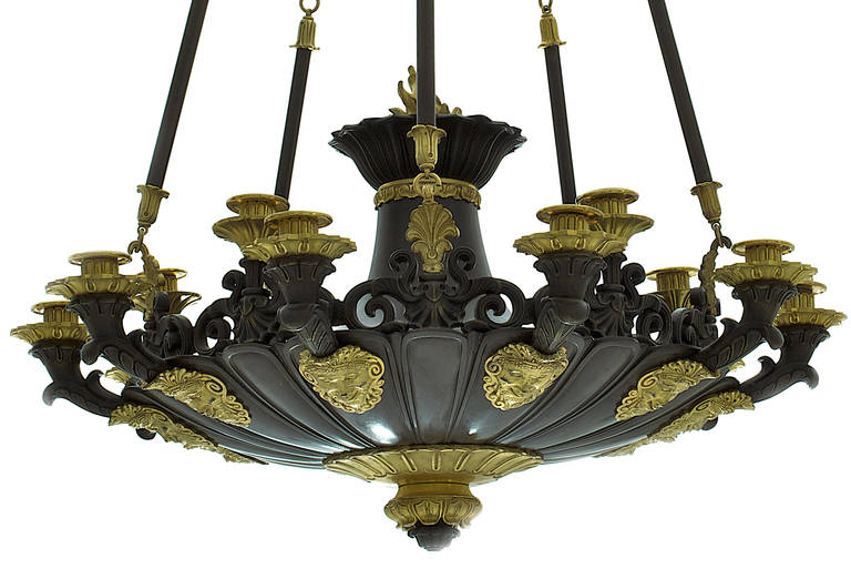 Chandelier with fifteen lights attached to the crown by chains. The cup adorned by masks of satyrs is topped by a flame.