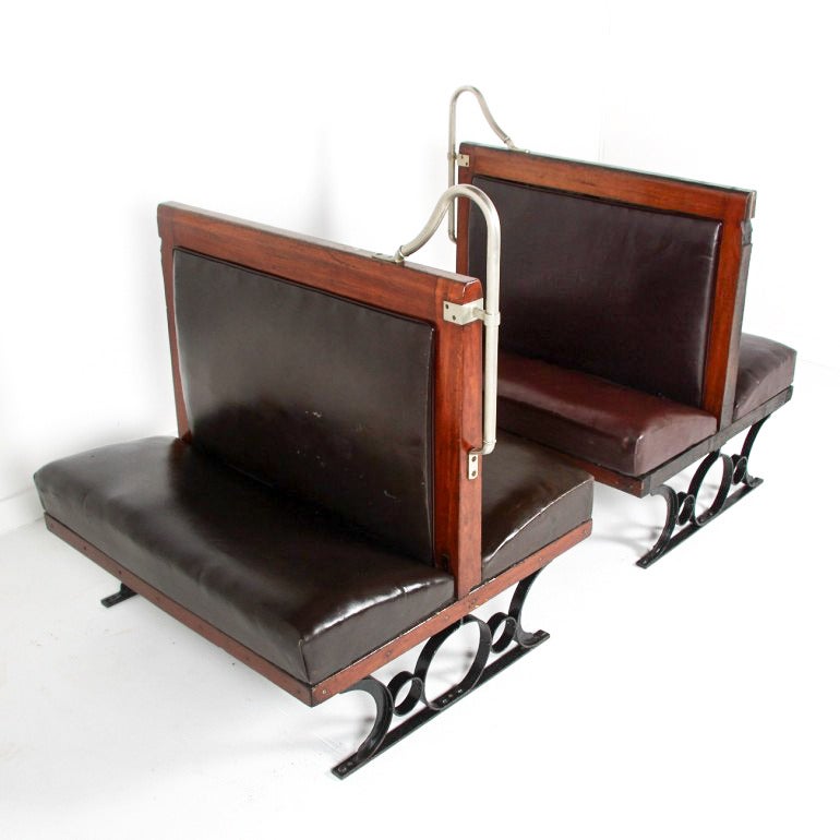 Pair of matched banquettes from the Paris Metro, circa 1910. Original condition, with chrome grab handle on wood frame. Upholstered in black leather, one marked 