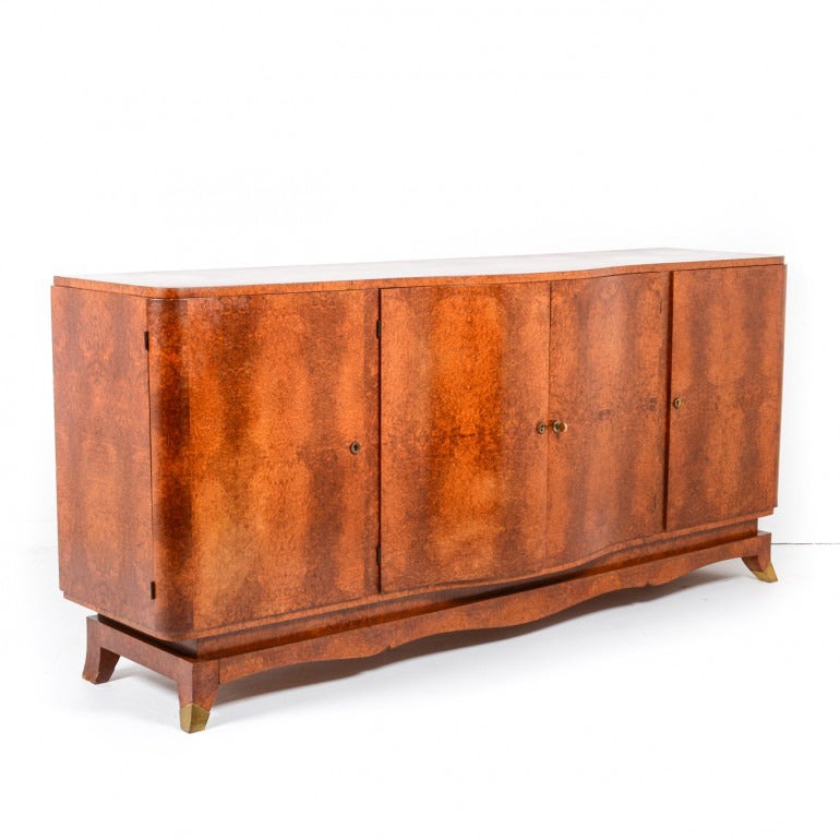 Classic art deco sideboard with genuine amboyna veneers and brass hardware. Clean lines true to the style with decorative scroll apron and splayed/capped feet. Interior drawers feature inlaid veneers on solid core. Original condition. Matching table