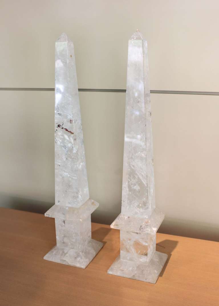 Pair of large-scale Brazilian rock crystal obelisks. Simple, traditional form with a long taper, beveled edge and square plinth base. Polished crystal with natural veins, adding interest and depth to these highly decorative pieces.
    