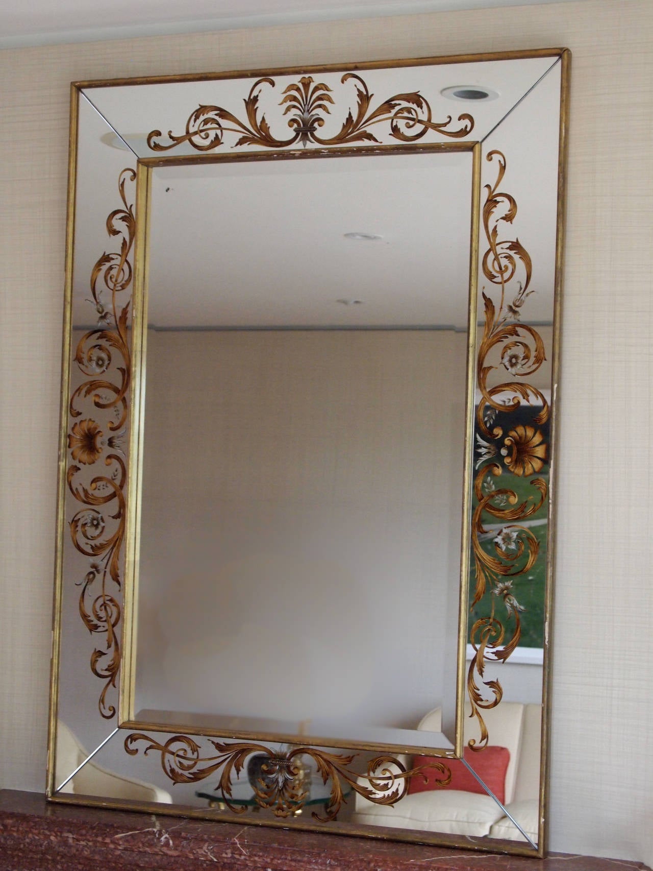 Beautiful large-scale églomisé mirror with gilt scrolls. Original condition with some minor blooming to silver backing and minor losses to wood gilding.