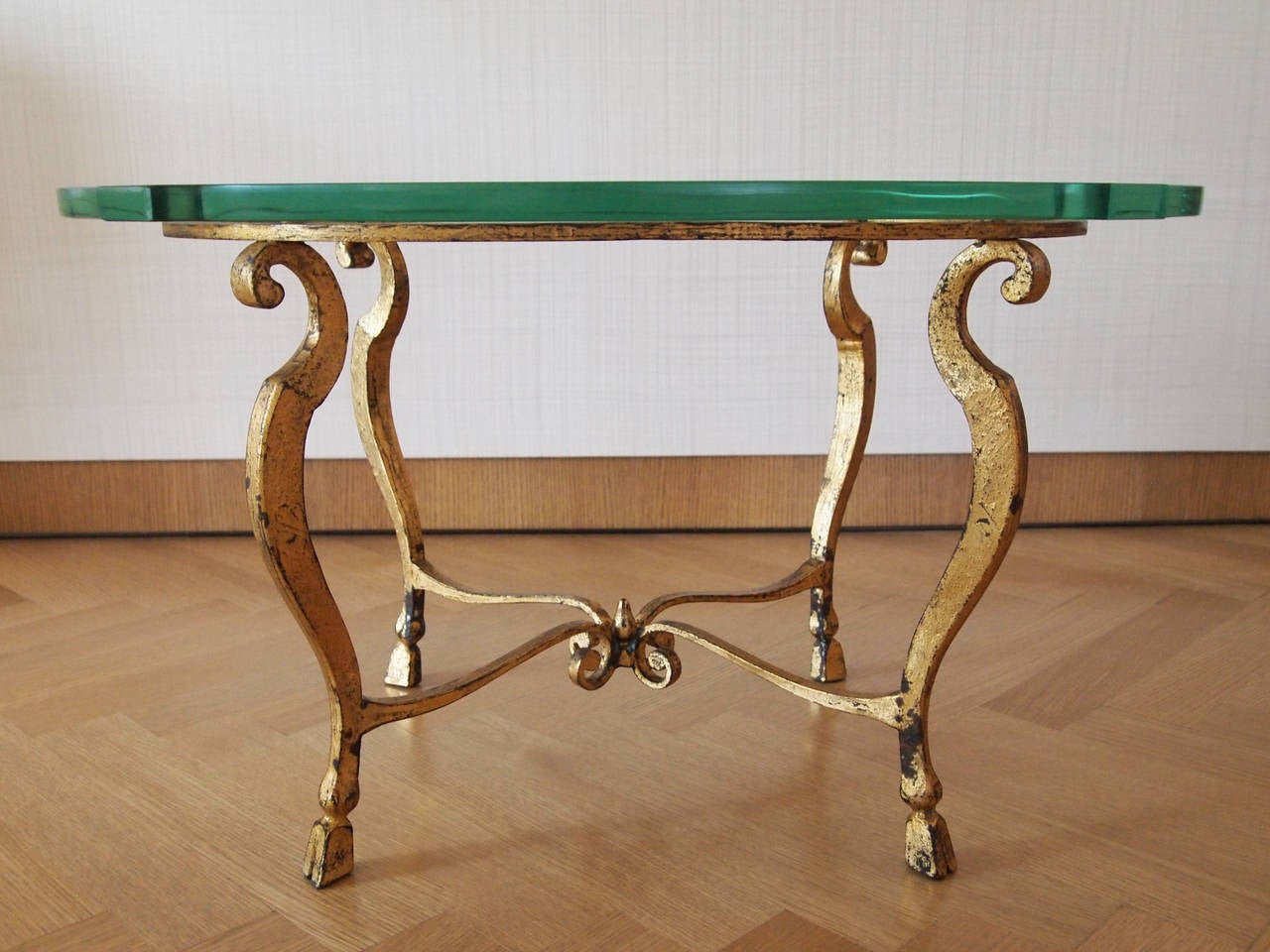 Beautiful side table with a strong attribution to Maison Ramsay. Thick glass top with gilt bronze base comprised of hoofed feet and scrolled stretchers.