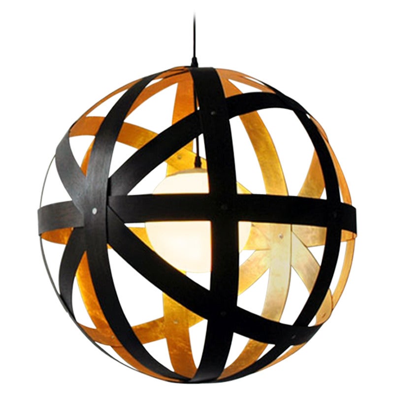 The Meridian 24" pendant is a study in implied motion. Bands of locally sourced black and gold leaf walnut surround a glass orb mounted and hung from a cord and aluminum canopy.

Meridian is a versatile product and can be specified in five