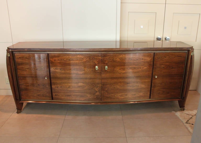 Credenza by Maurice Rinck circa 1940. Stunning streamlined composition with brass mounts and lockable cabinets, each with two shelves (key not included). A highly polished and well preserved piece of furniture, restored circa 2000. 
