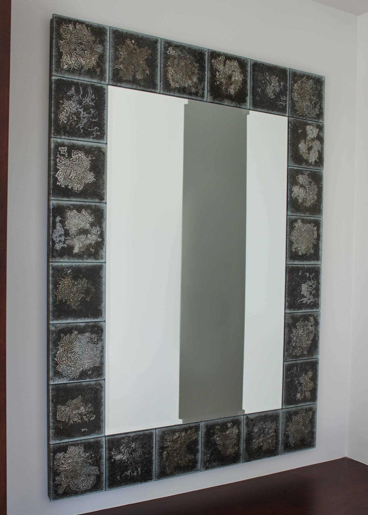 Pair of glazed tile mid-century mirrors. Perfect original condition, each tile is unique with a crystallized metallic motif over green-grey.
