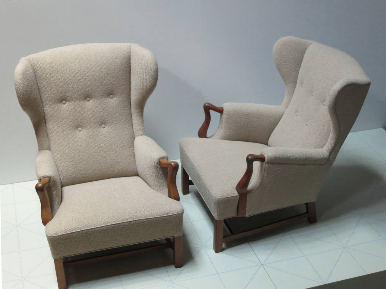 These generous and comfortable chairs were made in the 1940s by master cabinetmaker and designer Jacob Kjær. The seats and seat backs are fully sprung and have been newly upholstered in a cafe-au-lait colored nubby wool fabric. The hand carved