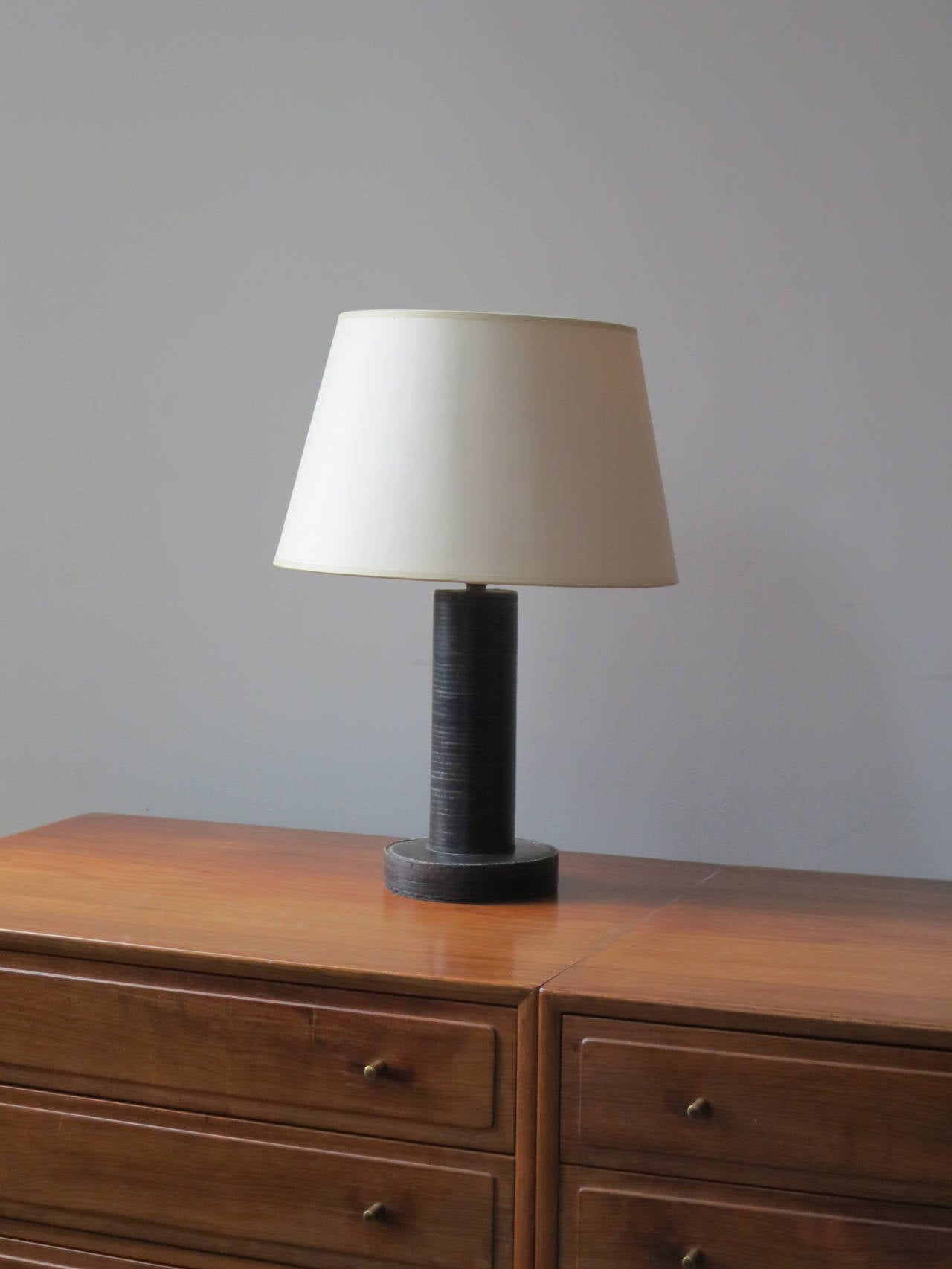 Early table lamp by Paul Dupré-Lafon and Hermès with base and cylinder in black stacked leather.

Stamped in gold on the underside of the base: HERMÈS-PARIS / DÉPOSÉ.

Height without shade: 8 1/4 inches (21 cm.)
Height with shade: 16 inches (40.7