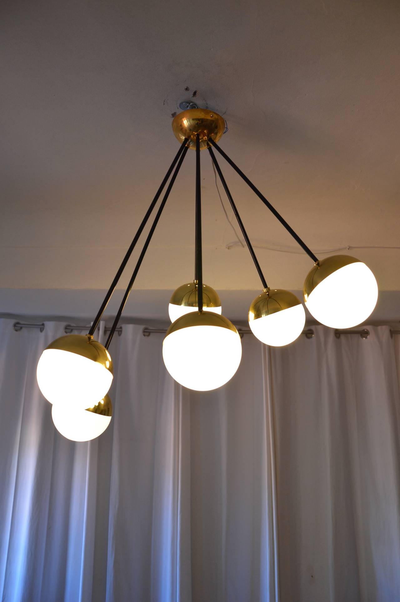 Celling light in brass  by Stilnovo with globes in white glass. 6 glass, with different lengths. Possibility to change the length. 
Measures :  H max : 70cm  Diameter circa : 60cm  Diameter of a globe : 10cm