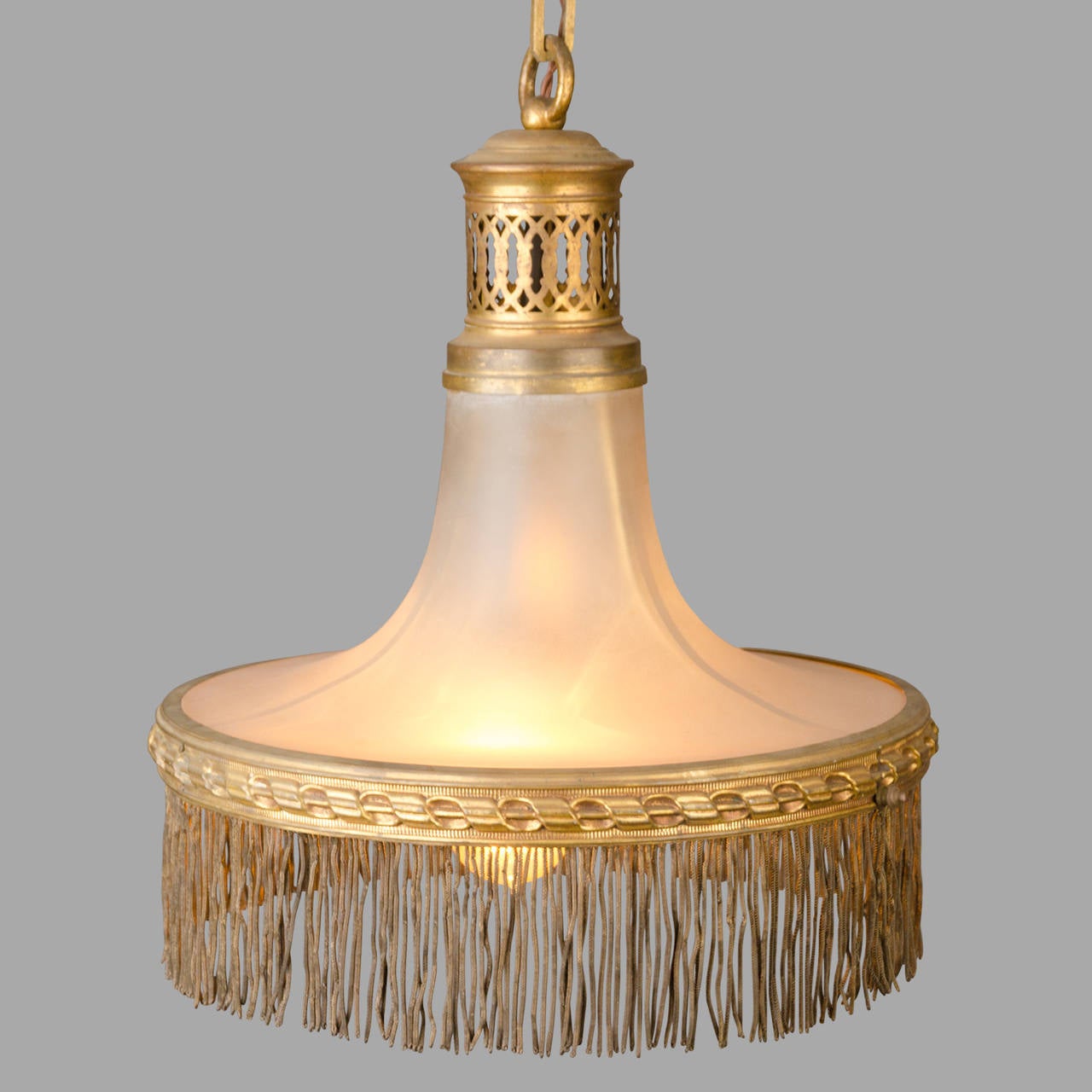 Brass pendant light with a glass reflector, circa 1920. Decorative brass fringes.