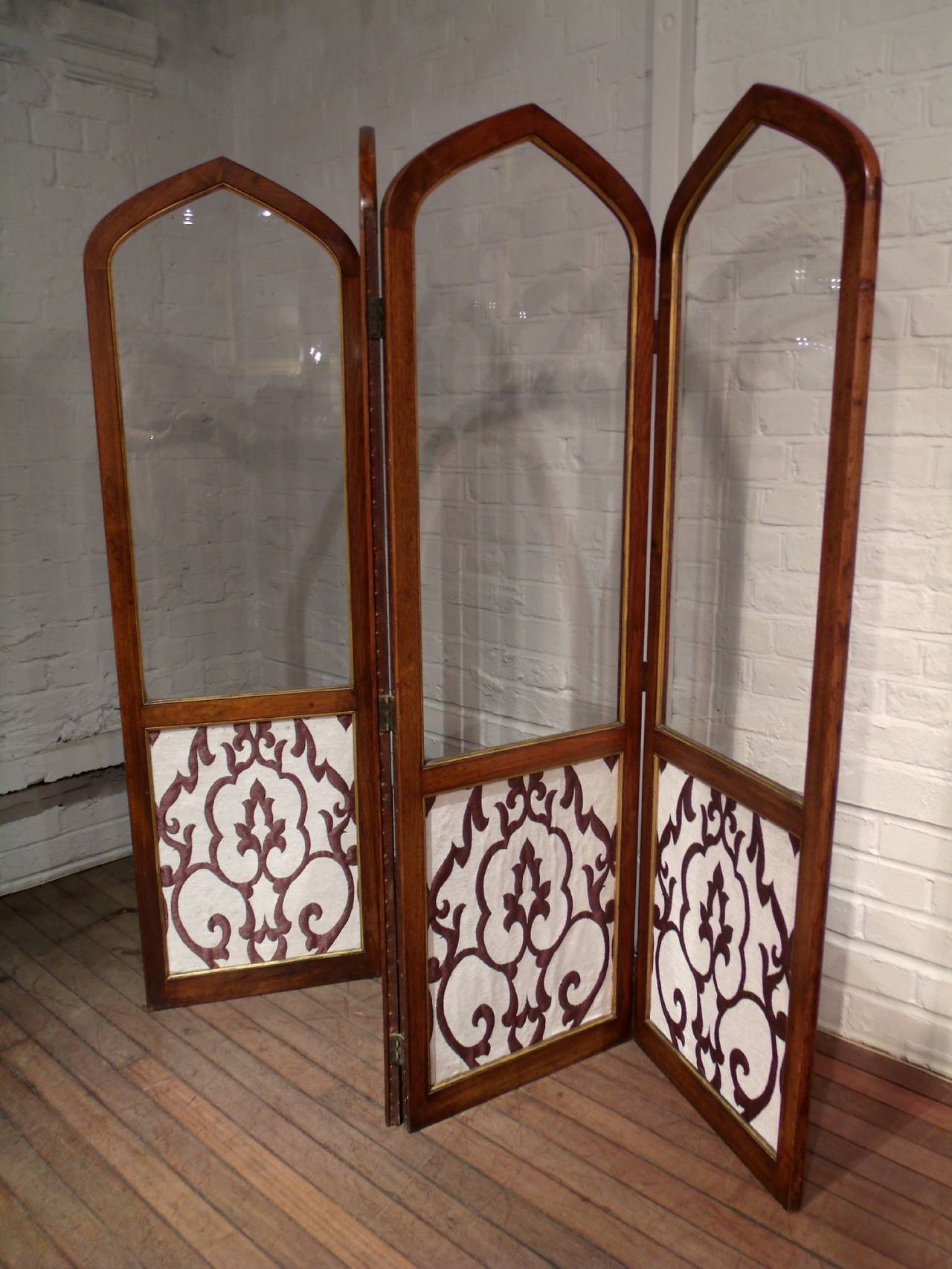 This very handsome and solid Victorian walnut and parcel gilt Gothic four-part folding screen features a glass top sections with smaller fabric covered panels on the bottom. Each panel measures 18 in – 45.7 cm in width, for a total of 72 in – 183 cm