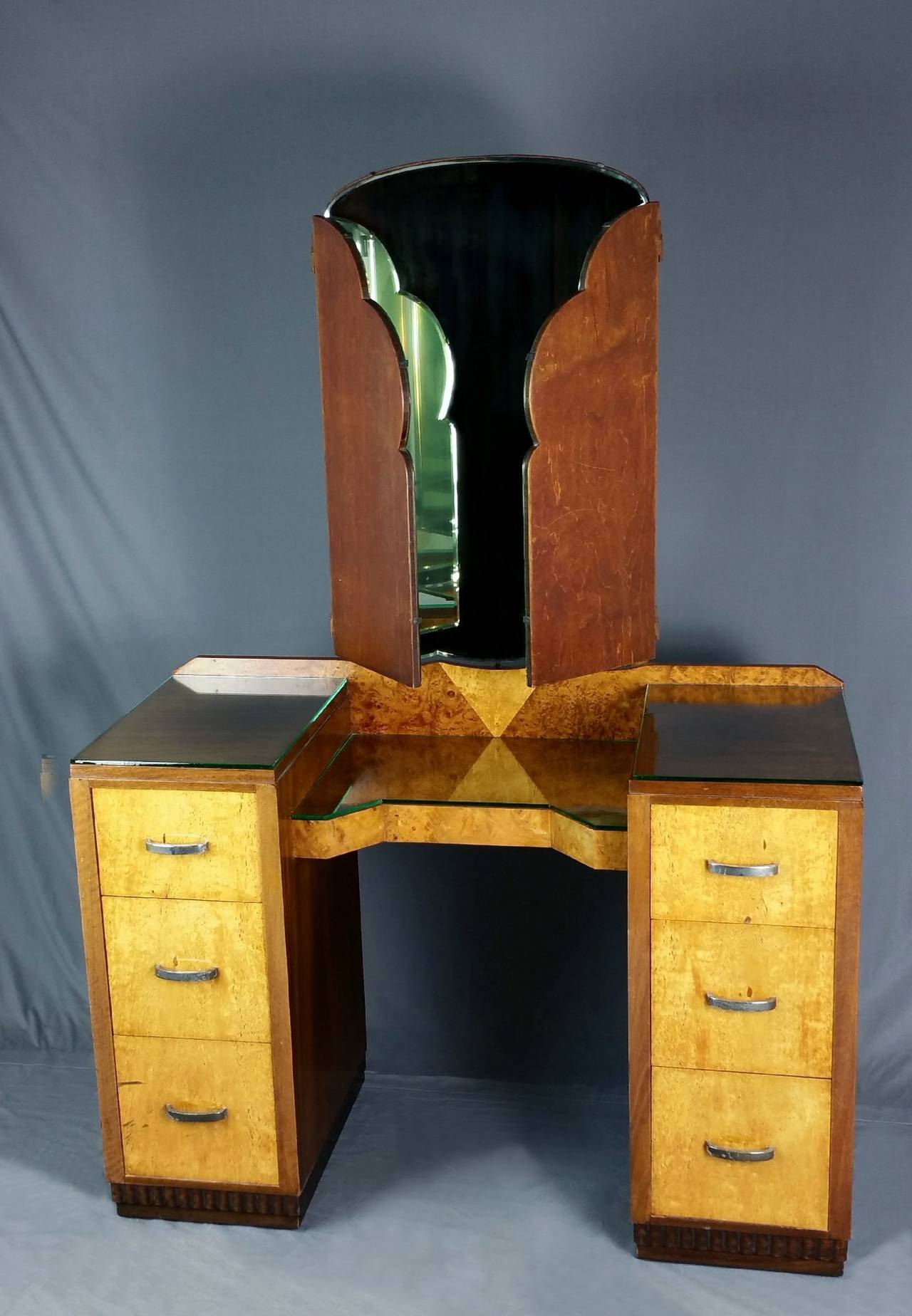 This splendid Art Deco pedestal dressing table is comprised of mahogany, maple and burr walnut woods. The dressing table features the original chrome handles and triple bevelled mirrors. The center mirror also can be tilted forward and back, with