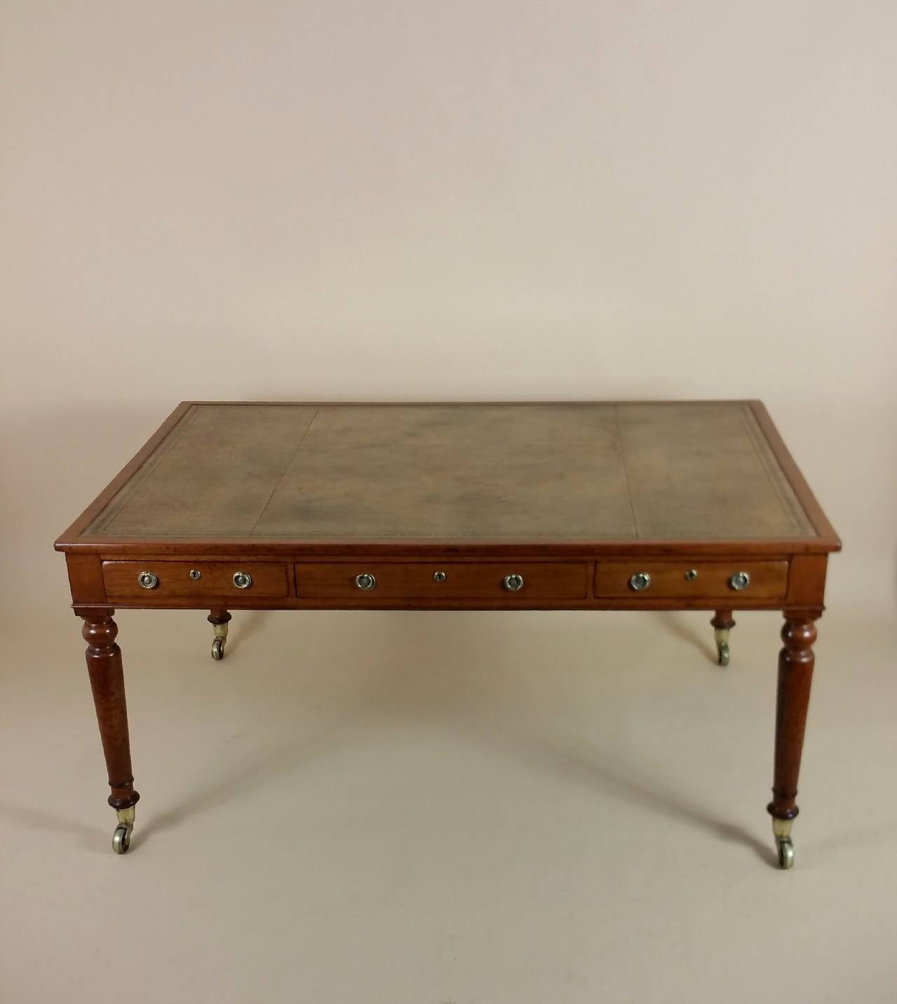 This fine quality and extremely handsome Victorian mahogany writing table features large and sturdy brass castors on tapered turned legs and brass hardware. The table was made by S & H Jewell of London, well known cabinet makers of the period and