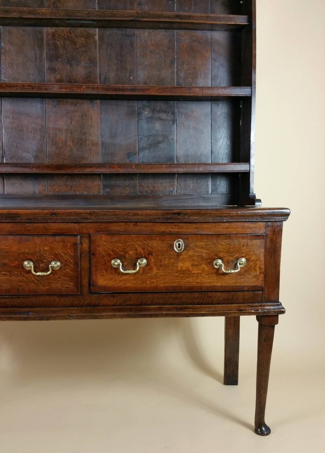 This gorgeous and superb quality oak cottage dresser is circa 1750, and features crossbanded mahogany decoration against a beautiful and rich patina. The dresser has three shelves with two spacious full length top drawers, with tapered front legs on