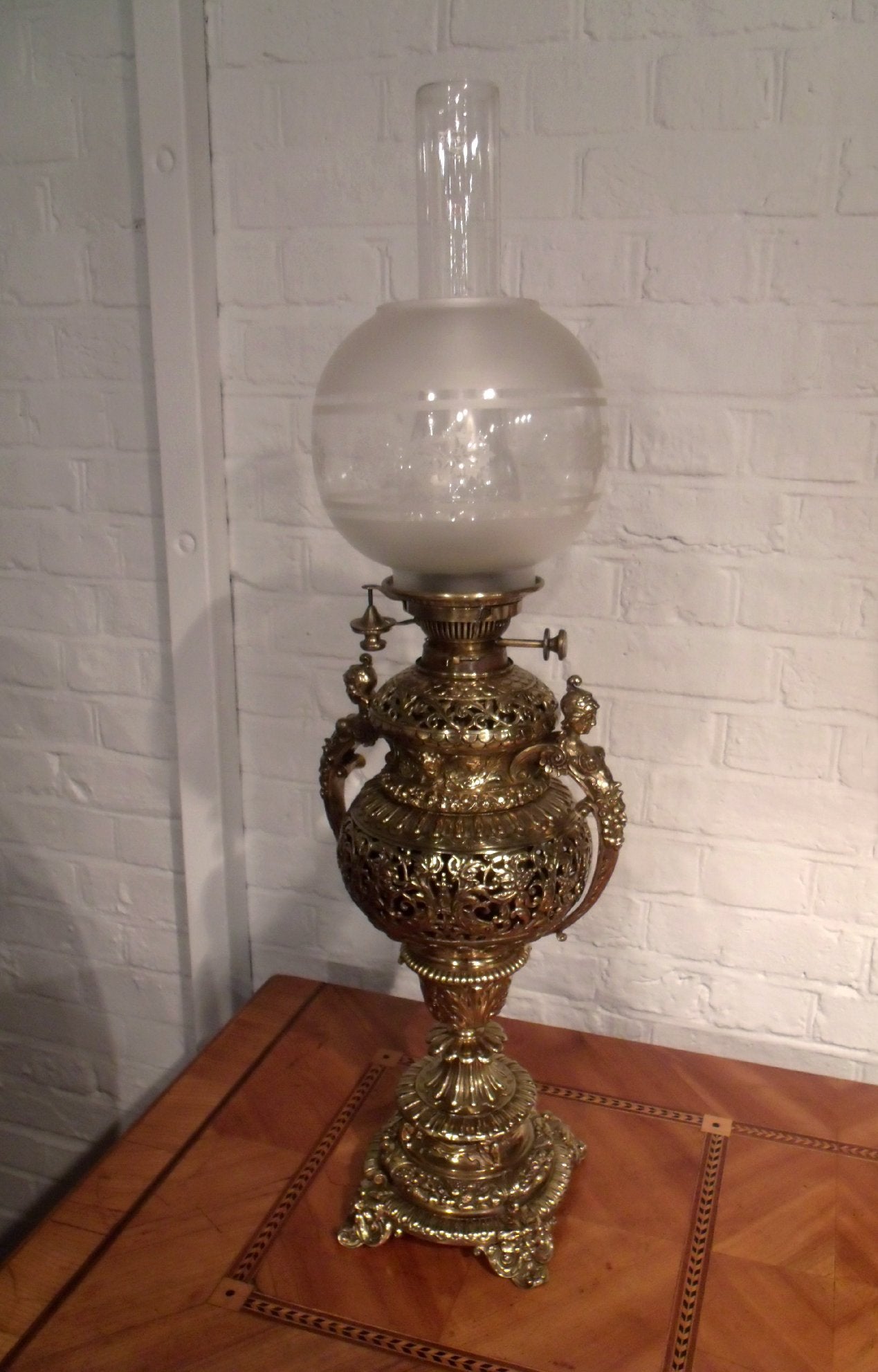 This beautiful Victorian brass oil lamp is a superb example of the period. The lamp base and body display an intricate and very ornate design of scrollwork and piercing. Each side is flanked by a centaur shaped handle, and along with the standard
