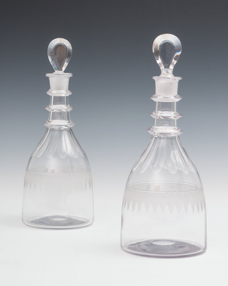 A fine pair of Georgian decanters engraved with feather bands and slice cut necks with three applied rings.