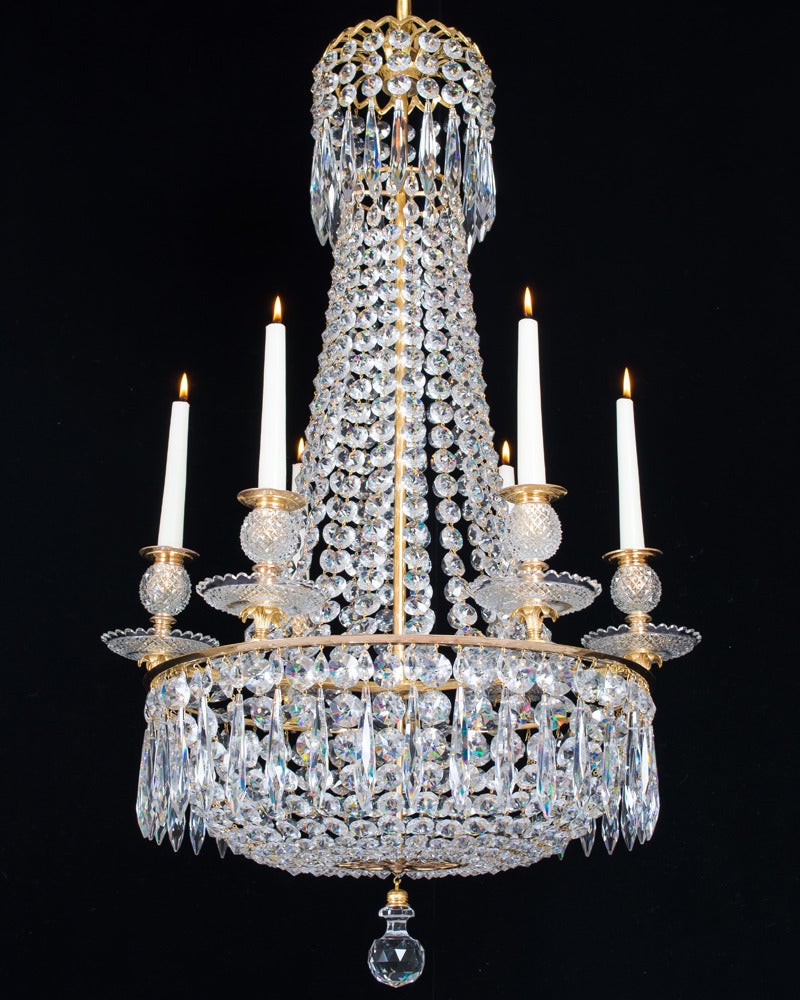 A fine pair of six light ormolu-mounted chandeliers of classic tent and basket form the main ring issuing six ormolu leafs supporting diamond cut drip pans and diamond cut ball candle nozzles. The chandelier is hung with the finest quality triple