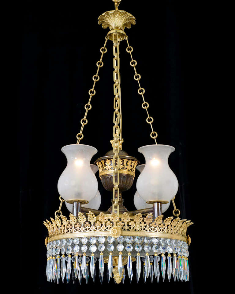 The top ormolu corona surmounted with four classic regency hanging chains these supporting a knurled and pieced leaf decorated band this surmounted by a bronzed and ormolu mounted four way colza centre original designed for oil burners and unusual