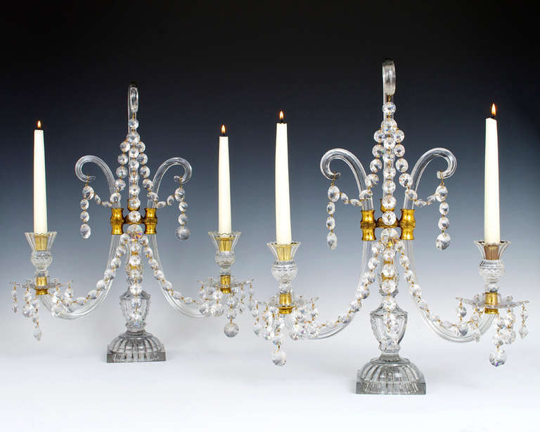 An important pair of English George III period cut-glass and brass-mounted two-light candelabra by Lafount, the candelabra supported by cut square bases with lemon squeezer inset below, the candle branches and central shepherd’s crook of ribbed