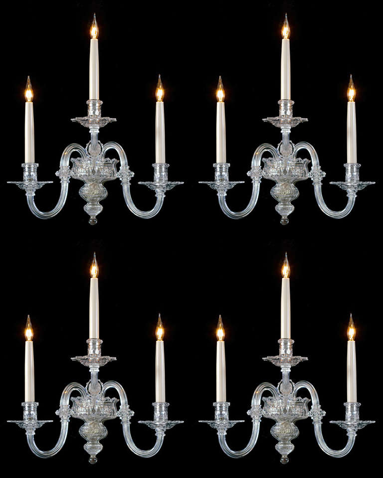 An unusual set of four cut-glass wall-lights by F&C Osler. The baluster shaped diamond cut-glass back plate surmounted with three very unusual candle arms these arms with diamond cut, pointed edged drip pans and diamond band candle nozzles the