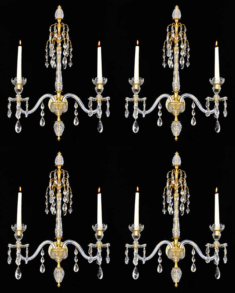 A fine set of four ormolu-mounted cut-glass two-light wall lights in Adam style the central diamond and slice cut-glass column surmounted by three drop hung ormolu sprays and a ormolu mounted diamond cut-glass egg. The ormolu back plate surmounted