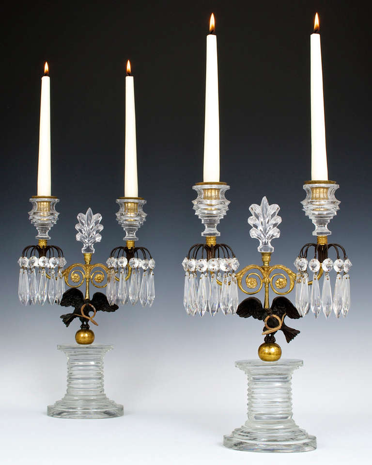 A fine quality and unusual pair of English Regency period candelabras the oval step cut base supporting a bronzed eagle with captured serpent above this the candelabra arm is centred by a cut-glass palm tree finial the candelabra arms surmounted
