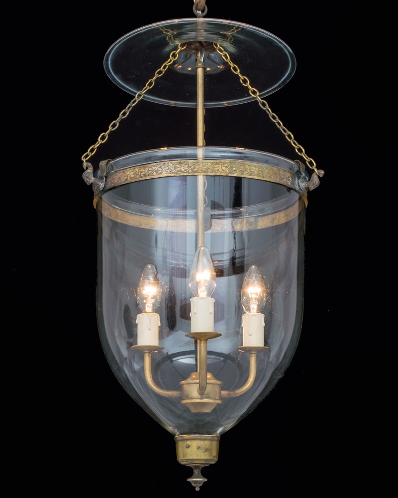A georgian glass lantern suspended form a decorative band on three chains terminating with a smoke bell.