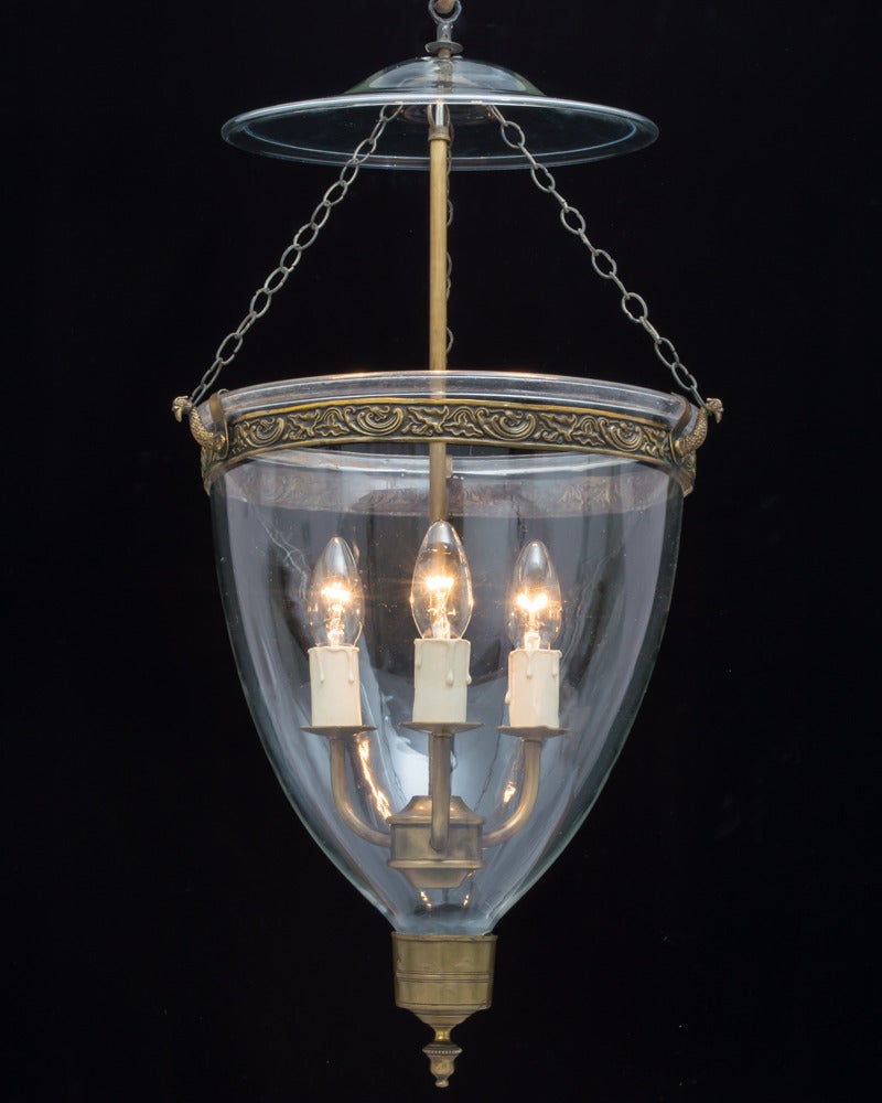 A georgian glass lantern suspended form a decorative band on three chains terminating with a smoke bell.