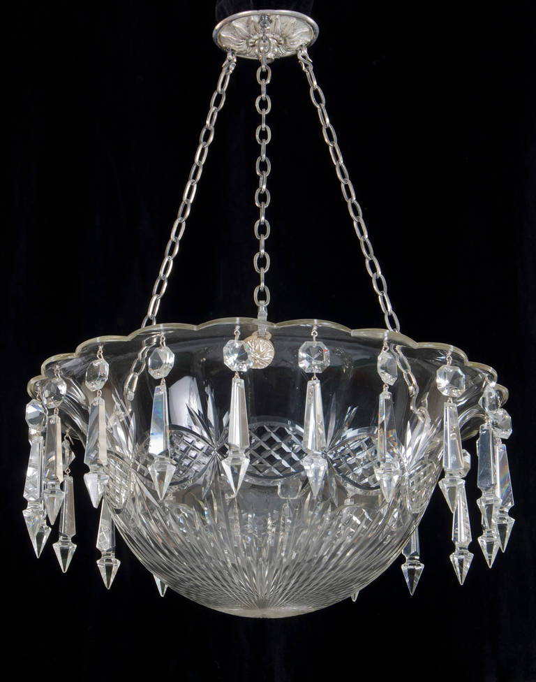 A fine quality cut glass bowl light suspended on three chains and leaf decorated silvered ceiling plate the bowl with scalloped edge and richly cut with oval panels the bowl hung with queen drops and Victorian spangles.