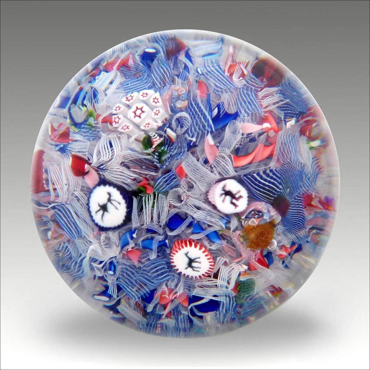 A Saint-Louis scramble paperweight with three silhouettes of a horse,devil and a dancing lady on a ground of coloured ribbons and some aventurine inclusions.
