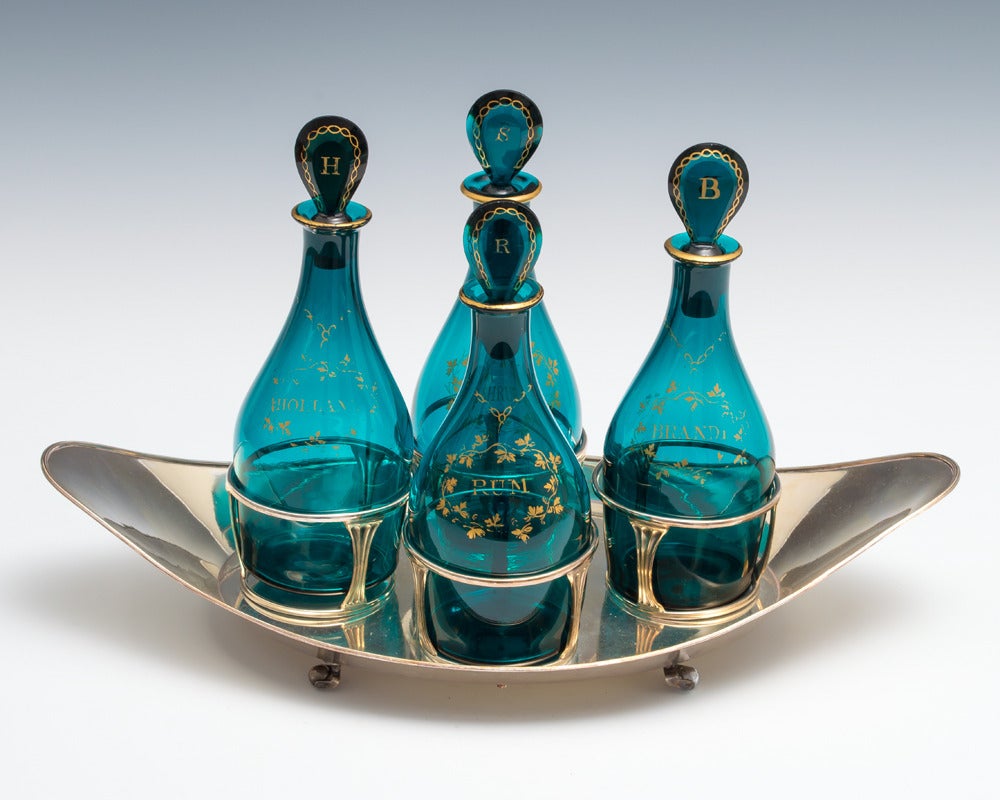 A fine set of four Georgian decanters with gilded labels and stoppers sitting in an unusual boat shaped sheffield plate stand.

Decanter size:
 
Height 8 1/2in (21.5cm),
 
width 3 1/4in (8cm).