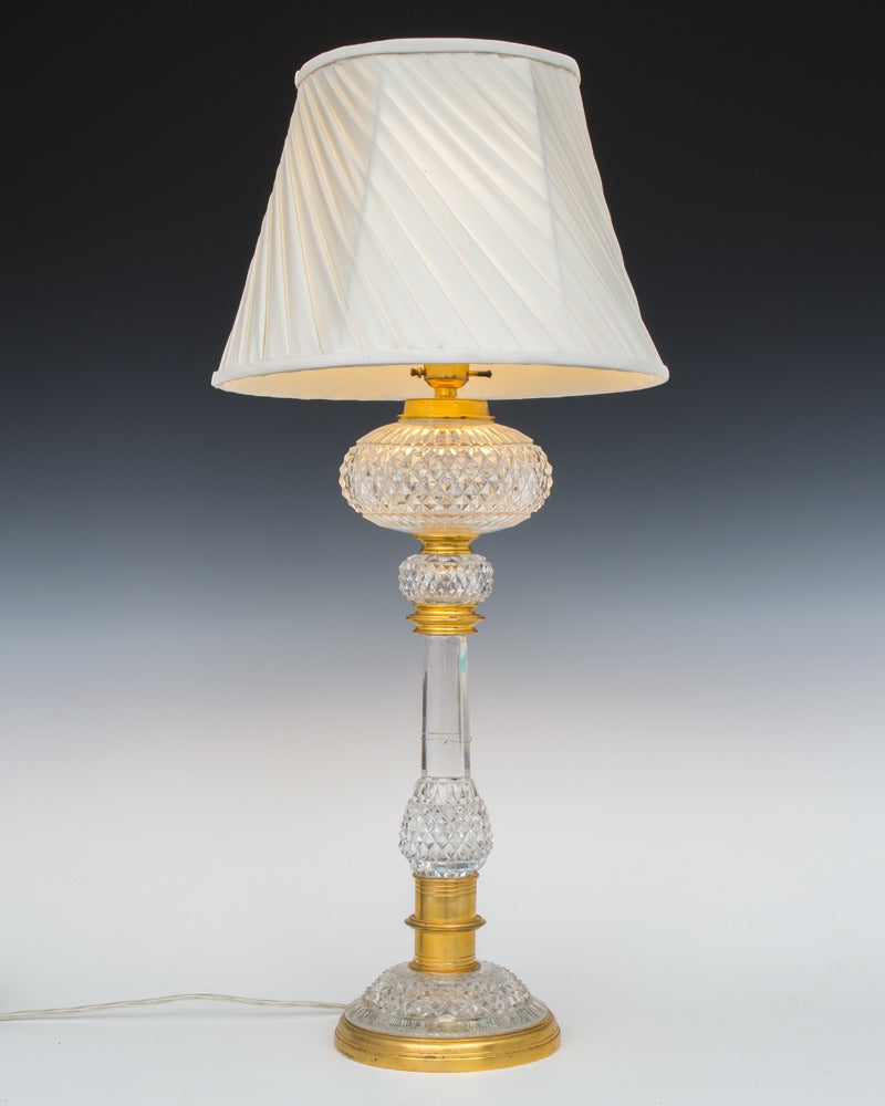 A ormolu mounted cut glass lamp the ormolu base with diamond cut foot mounting a diamond cut egg and slice cut column this further mounted with diamond cut ball and oil font.