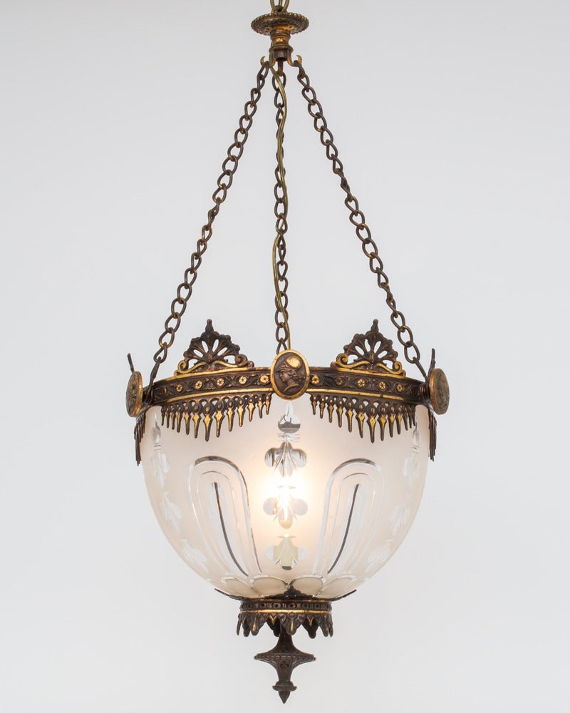 A fine mid-Victorian lantern hung on three chains supporting a most unusual scroll band with anthemion and serrated fans this mounting a frosted and engraved bowl terminating with further fretwork and cast final supporting a candle holder.