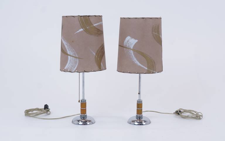 Beautiful pair of 1940s table lamps. Chromed steel base and stem with bakelite detail at the lower end of the stem. Original shades in very good condition.