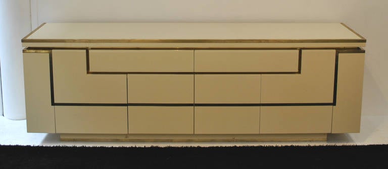 A very nice large sideboard by Jean Claude Mahey. Ivory lacquer with solid brass details.

Very good condition, with evident wear on the lacquer.