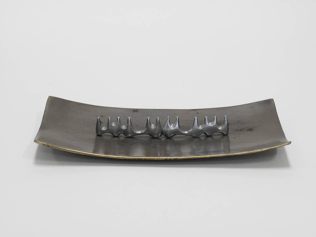 Long tray in brass-plated cast metal with a satin chrome, mountain range shaped row of cigar and cigarette resters lining the middle, designed by Ben Seibel and made by Maison Gourmet, a Product of Jenfred Ware, New York, 1950s.