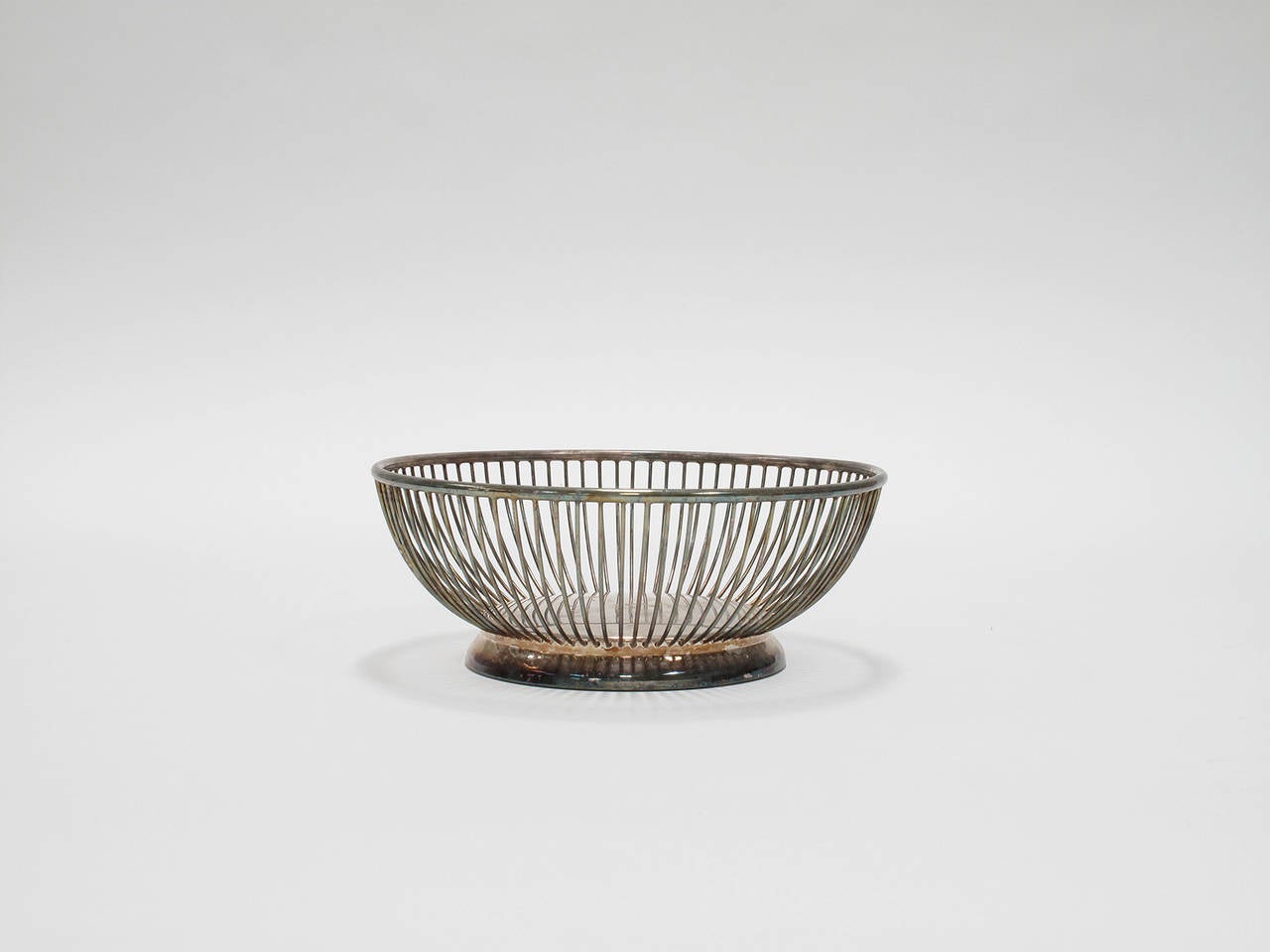 Decorative and functional, silver plated round wire basket for the display of breads, fruits or spools of imported cashmere.